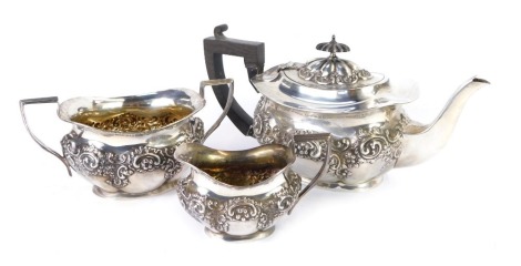 An Edward VII silver three piece tea set, of lobed form, embossed with flowers, foliate and rococo scrolls, comprising teapot, cream jug and sugar bowl, Birmingham 1901, 30.87oz all in.