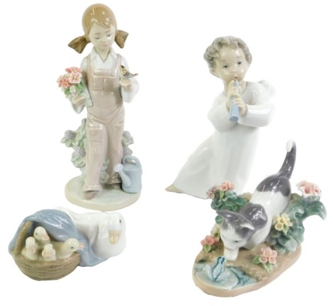 Four Lladro porcelain figures, comprising a girl in dungarees with flowers and a bird in her hand, a cherub playing an instrument, cat facing off with a frog, and a duck and ducklings in a basket.