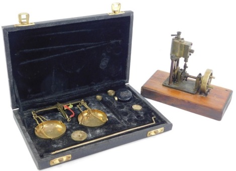 A set of gold scales, with weights, cased, together with a brass model of a pump engine on a wooden base. (2)