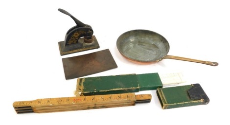 An early 20thC brass handled copper frying pan, cast iron company stamp, slide rules, a measuring stick, and a 19thC copper plate relating to R Bean of Boston. (a quantity)