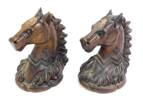 A pair of late 19thC oak carvings of horse's heads, each carved with a jagged collar and cross motif, 29cm high.