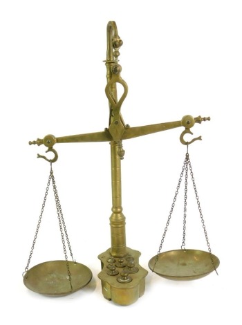 A set of brass balancing scales, with weights, on an integral base, 55cm high.