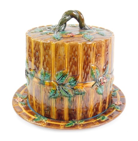 A majolica cheese dish and cover, of barrel form, moulded with flowers and leaves, number 1689, 30cm high. (AF)