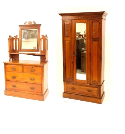 An Edwardian walnut bedroom suite, comprising single hanging wardrobe, enclosed by a single mirrored door with panelled front and carved detail, fitted with a drawer below, 190cm high, 100cm wide, 43cm deep, and a matching dressing chest of two short and 