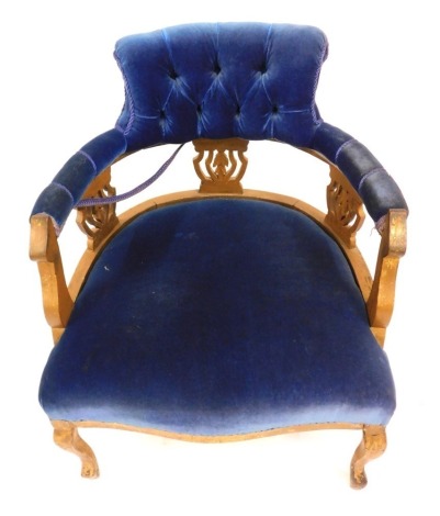 A late Victorian gilt wood low seated tub chair, with button upholstered back, padded arms and seat in blue plush material, the frame later painted gilt.