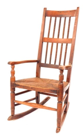 A 19thC rush seated open armchair, the high back with bobbin turned spindles, and with turned supports and stretchers and additional later rocking runners.