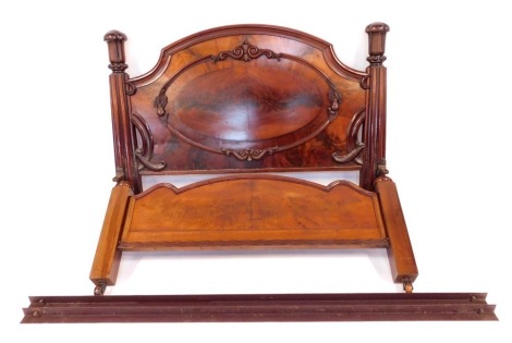 A Victorian figured mahogany bed head and foot, the bed head with arched top and with central oval panel and carved scroll ornamentation carved with pears and foliage, supported on heavy fluted and turned posts with mushroom finials and collars, the bed f