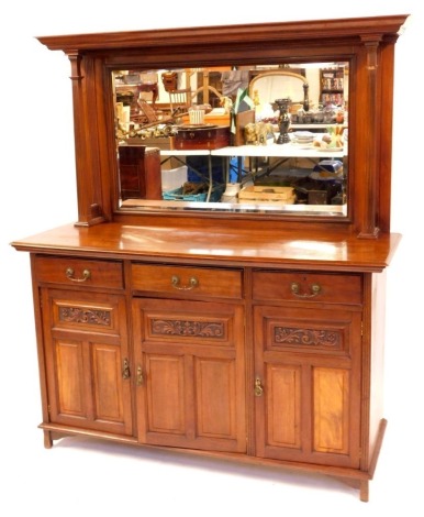 An Edwardian walnut mirror back sideboard, the mirror back with plain moulded cornice and square reeded pillar supports incorporating a bevelled rectangular mirror, the base with three drawers and corresponding cupboards below having carved and fielded pa