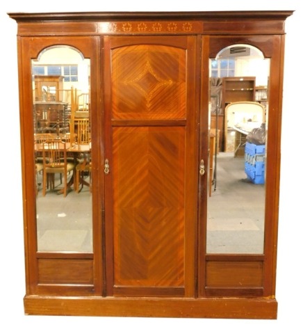 A George V inlaid mahogany triple wardrobe, with moulded cornice with inlaid frieze, panelled door below flanked by two arched mirror doors, 212cm high, 188cm wide.