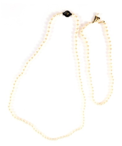 Two cultured pearl necklaces, comprising one with white lustre cultured pearls on knotted string strand, beads 5mm wide, with a fan design clasp, yellow metal stamped 375, with pearl droplet, 40cm long, and a cultured pearl white finish pearl necklace, wi