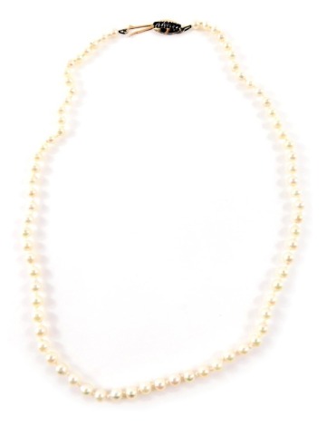 A cultured pearl single strand necklace, with pink finish lustre bears, on a knotted string strand with yellow metal clasp, set with five aquamarines, yellow metal stamped 375, 66cm long, 12.1g all in.