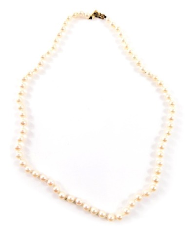 A single strand cultured pearl necklace, with white lustre finish beads, on a knotted string strand with a yellow metal bow clasp stamped 375, 56cm long, 25.1g all in.