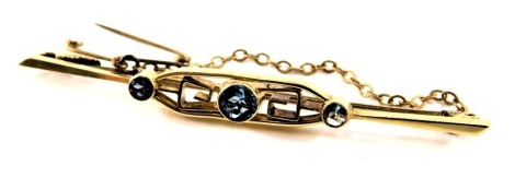 An Art Deco blue zircon set bar brooch, with Greek key design, on single pin back with safety chain, yellow metal unmarked, 6cm wide, 4.2g all in.