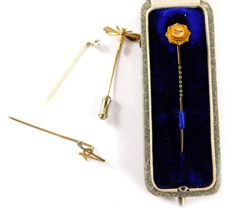 Four stick pins, comprising a 9ct gold A stick pin set with tiny diamond, 0.8g, a 15ct gold topped and diamond stick pin, and two plated pins. (4)