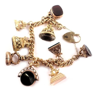 A 9ct gold charm bracelet, the curb link bracelet with heart shaped padlock and safety chain, applied with nine various gilt seal fobs set with crested stones to include moonstone, bloodstone, orange agate, tiger's eye, citrine and jet, yellow metal and o