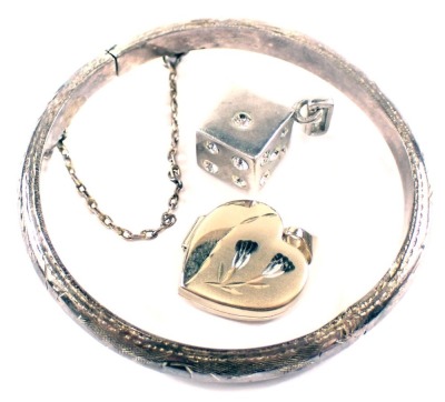 A silver child's bangle, 4cm diameter, 5.7g, a 9ct gold heart shaped locket, and a plated dice pendant. (3)