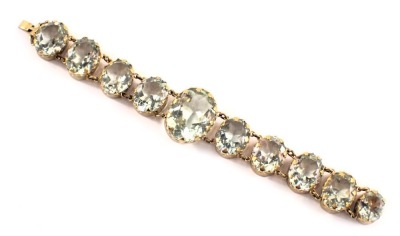 A 1920s style bracelet, with graduated pale blue oval glass beads, each in a rub over gold coloured setting, 18cm long. (AF)