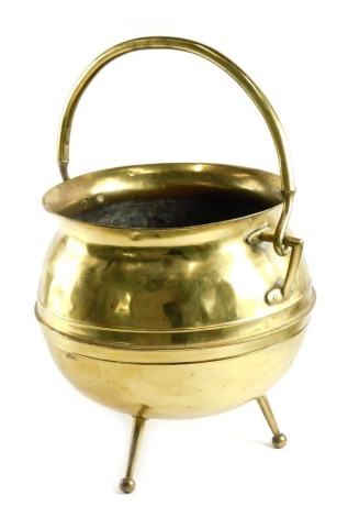 A late 19thC brass coal bucket, in arts and crafts style, of cauldron form with tapering legs and loop handle, stamped monogram to underside, possibly Sankey, 34cm high. (AF)