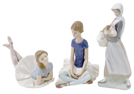 Three Lladro figures, comprising a seated ballerina, a lady standing with hen and basket, and a blue topped seated ballerina, the largest 21cm high. (3)