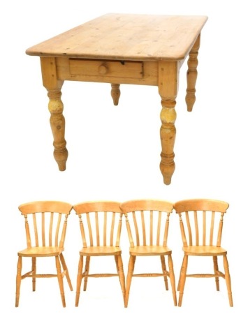 A pine kitchen table, the planked top with rounded corners, on turned legs, 76cm high, 138cm wide, 83cm deep, and four slatted kitchen chairs.