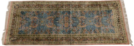 A Persian silk runner, with all over floral and leaf design, on a blue ground with multiple borders, 88cm wide, 236cm tall.