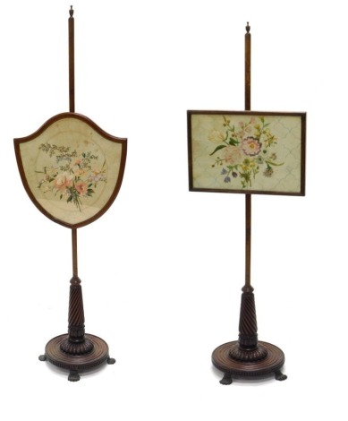 Two 19thC mahogany pole screens, each with a differing banner, one shield shaped embroidered with flowers, the other rectangular, each on a spirally turned and plain column and reeded circular platform with metal paw feet, 145cm high. (2)