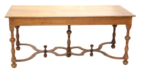 A Continental walnut dining table, the rectangular top with a moulded edge above plain frieze, on turned supports with elaborate pierced shaped flat stretcher, on bun feet, 77cm high, 180cm wide, 74cm deep.