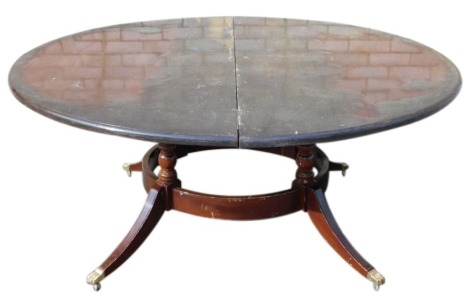 A Regency style circular extending dining table, with halo base, sabre legs and brass paw castors, 183cm diameter min. (AF)