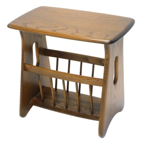 An Ercol mid coloured elm Canterbury, the rectangular top with rounded edges and corners, on pierced end supports, 52cm wide.