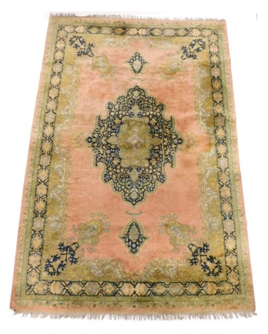 A machine woven large rug or small carpet in Turkish style, with a central medallion in navy blue on a pink ground 190cm wide, 280cm tall, with part gold coloured spandrels.