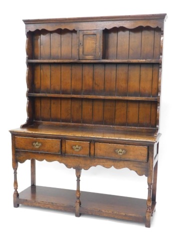 A Titchmarsh & Goodwin oak dresser in 18thC style, the raised back with panelled door, and two shelves for plates, and shaped sides, the base with three frieze drawers above shaped apron on turned supports with pot board, 137cm wide.