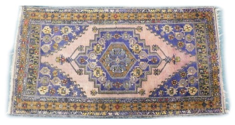 A Turkish type rug, decorated with a large mainly purple medallion, on a pale red ground with purple pattern spandrels, one wide and two narrow borders, 191 x 100 cm.