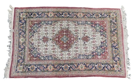 A Persian style mercerized cotton rug, the central pole medallion in mainly red, on a beige ground with red spandrels, one wide and two narrow borders, 90cm x 143cm.