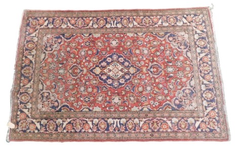 A Persian rug, with a central blue pole medallion, on a red ground with blue spandrels, one wide and various narrow borders, 196cm x 129cm.