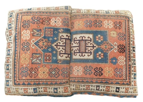 A pair of floor cushions, each covered with a fragment from the same Persian Kazak style rug or runner, 90cm x 69cm. (AF)