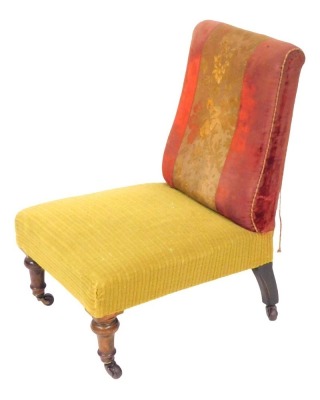 A Victorian mahogany nursing chair, upholstered in contrasting seat and back, raised on turned legs, brass capped on castors.