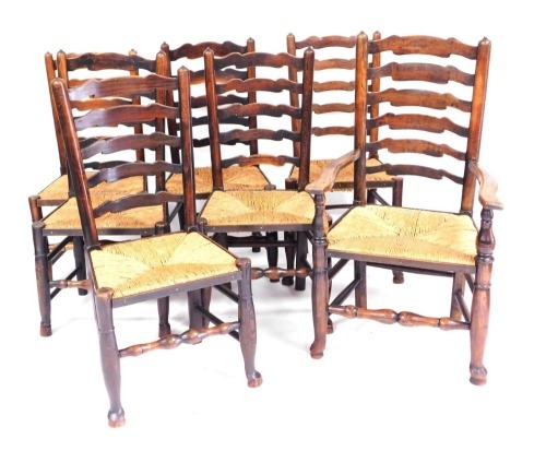 A set of seven Georgian oak and rush seated ladder back dining chairs, raised on turned legs, on pad feet, united by turned stretchers, comprising a carver chair, 61cm wide and six single chairs.