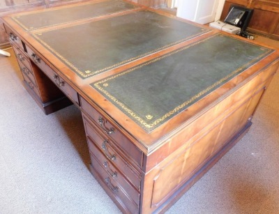 A 20thC yew partner's desk, the top with three green gilt tooled leather insets, with a moulded edge, with an arrangement of four drawers, sliding shallow drawer and two faux drawer cupboards to each side, on a plinth base, 75cm high, 180cm wide, 127cm de - 2