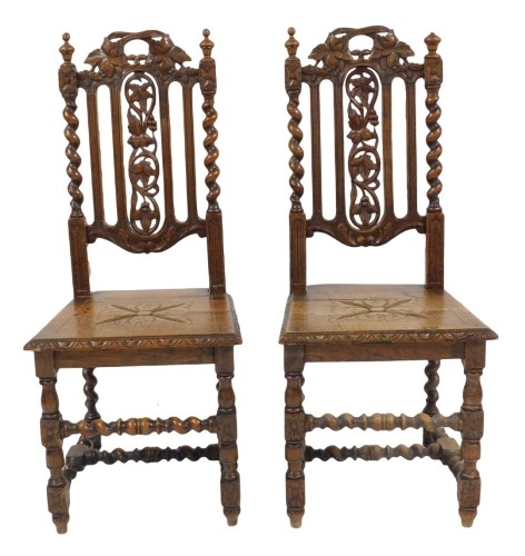 A pair of Victorian oak dining chairs in 17thC style, each with a pierced carved leaf and fruit back, with spiral twist supports with solid seat, on turned and carved legs united by spiral turned stretchers. 