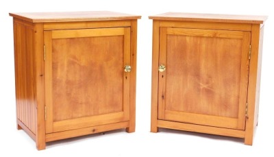 A pair of pine bedside cabinets, each rectangular top above a panelled door enclosing single shelf, on stiles, 70cm high, 65cm wide, 44.5cm deep.