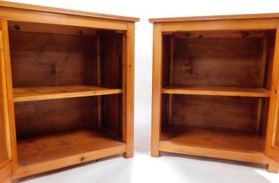 A pair of pine bedside cabinets, each rectangular top above a panelled door enclosing single shelf, on stiles, 70cm high, 65cm wide, 44.5cm deep. - 2