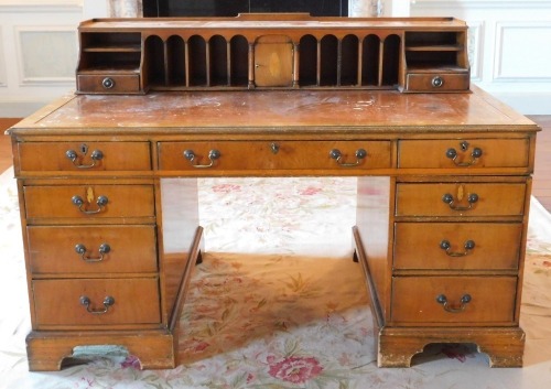 A 20thC yew desk, the raised top with an arrangement of recesses, central cupboard and drawers, etc., with a gilt tooled leather inset above a central frieze drawer flanked by two four drawer pedestals, on bracket feet, 105cm high, 152cm wide, 92cm deep.