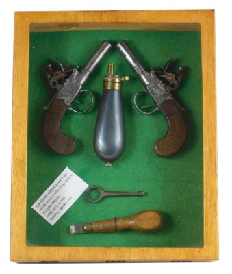 Two early 19thC flintlock muff pistols, by Rock & Sons, 15cm long, together with a turnkey, 7.5cm long, powder flask, etc., contained in an oak case, 31.5cm x 26cm.