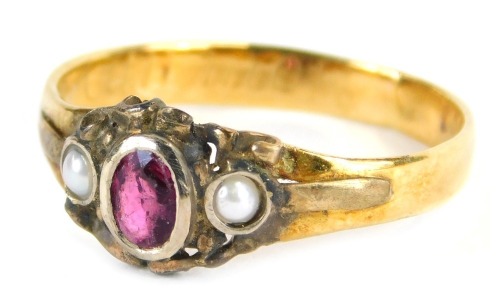 A Victorian dress ring, set with oval cut garnet in white metal rub over setting, flanked by two seed pearls, on a later yellow metal band, unmarked, but bearing partial rubbed inscription, ring size N, 2.1g all in. 