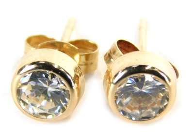 A pair of stud earrings, each with imitation diamond, in a rub over setting on single pin back with butterfly backs, yellow metal, marked 375, 0.8g all in, boxed.