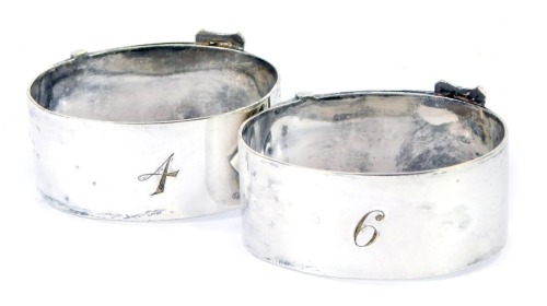 Two George V napkin rings, of buckle and strap oval form, numbered 4 E-9, silver plated, bearing initials A & J.