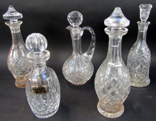 A group of cut glass decanters, comprising decanter of mallet form with stopper, 33cm high, two similar decanters of bottle form, with stoppers, one Waterford, 33cm high, together with a cut glass claret jug add stopper, silver port label, etc.