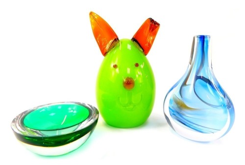 A group of Art Glass, comprising a Swedish glass vase of compressed bottle form, decorated internally in blues and whites signed to base CJ Tinback Sweden, numbered 4833, 22cm high, a green glass Murano bowl, and a green and red glass dog, 33cm high. (3)