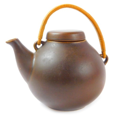 An Arabia pottery Oriental influence teapot, in brown glaze with a wicker handle, stamped to underside Arabia Made in Finland, 16cm high.