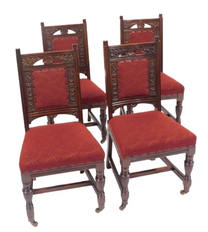 A set of four late Victorian mahogany single dining chairs, each with a carved back with floral motifs, overstuffed seat and back, on turned tapering legs united by H shaped stretcher, on castors.